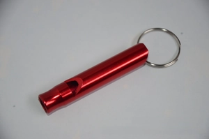 Close-up of red aluminum survival whistle with a portable metal key ring for outdoors