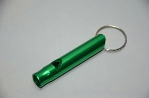 Close-up of green aluminum emergency whistle with metal keyring on a plain background
