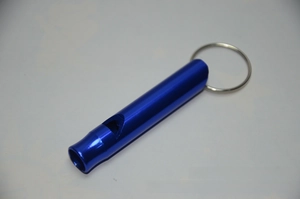 Close-up of blue aluminum survival whistle with metal keyring for outdoor emergency