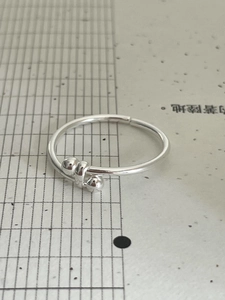Detail of minimalist 925 sterling silver open ring with dual bead charms and adjustable band