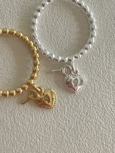 Detail of beaded rings with heart lock and key pendants in gold and silver finish