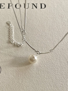 Close-up of a 925 sterling silver knot necklace with a white pearl and curved bar