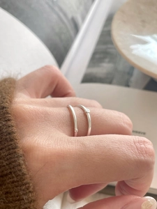 Close-up of dual minimalist 925 silver rings with tiny beads worn on female hand
