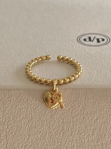 Macro view of gold heart lock and key charms on a dainty beaded chain open ring