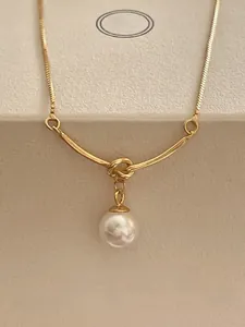 Detail of a 925 sterling silver gold-plated knot necklace with a round white pearl