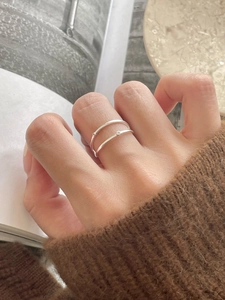 Close-up of a minimalist silver double-layer ring with a small zircon on a model's finger