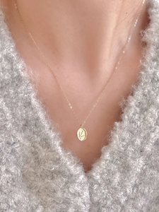 Close-up of a 925 sterling silver swallow necklace pendant on an oval gold-plated plaque