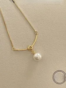 Macro detail of 925 silver pearl pendant with knotted gold finish and box chain