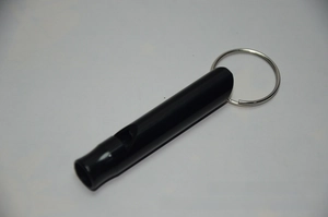 Detail of a black aluminum survival whistle with metal keyring for outdoor camping