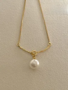 Detail of a 925 sterling silver gold knotted pendant necklace with white pearl