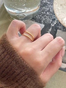 Detail of double-layered gold ring with zircon stones on model wearing brown sweater