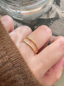 Close-up of dual-band gold-tone ring with sparkling zircon stones worn on hand