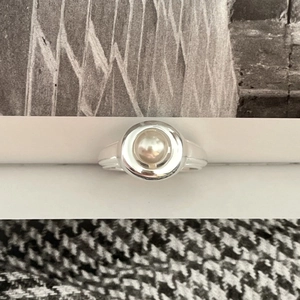 Minimalist 925 sterling silver open ring with a round white pearl on a white stand