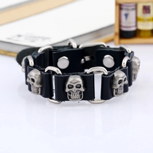 Punk black leather bracelet with silver skull charms and metal rings on a white surface