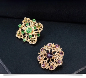 Gros plan de broches dorées vintage avec strass verts et violets sur cuir noir élégant