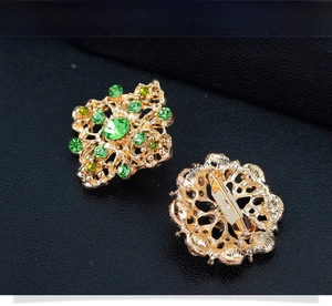 Vue détaillée avant et arrière de broches fleurs vintage dorées avec strass verts brillants