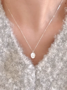 Close-up of a 925 sterling silver swallow necklace with an oval embossed coin pendant