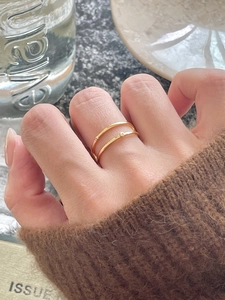 Detail of minimalist double-layered gold ring with a sparkling zircon on the finger