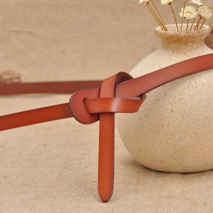 Minimalist brown leather skinny belt for women's dresses tied in a knot on rustic linen