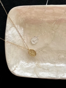 Detail of bird embossed oval pendants in gold and silver finish on textured stone
