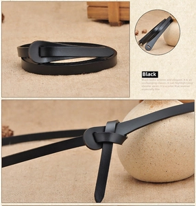 Detail of minimalist black leather skinny belt featuring a creative knotting style on linen