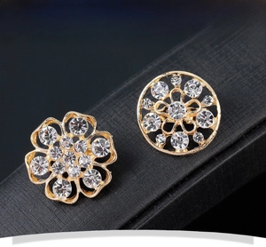 Vue macro de boucles d'oreilles fleuries dorées avec strass brillants sur support noir