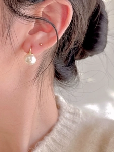 Close-up of a 12mm freshwater pearl earring on a model with an 18K gold hook