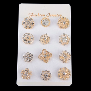 Lot de 12 broches en cristal doré soigneusement disposées sur une carte de bijoux blanche