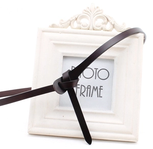 Close-up of a dark brown leather belt with an artistic knot design on a white frame