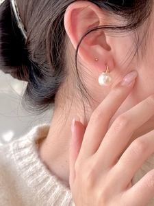 Close-up of a 925 sterling silver pearl hoop earring worn by a model in soft lighting