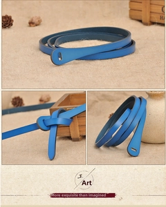 Detail of slim bright blue leather belt with black oil edges on a rustic linen background