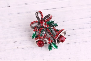 Detail of Christmas bell brooch with red and green rhinestones on vintage silver metal