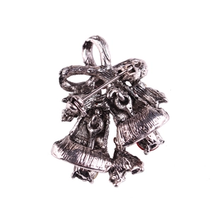 Vintage silver Christmas bell brooch with bowknot and red accents on white background