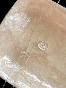 Macro detail of a 925 sterling silver swallow pendant necklace with elegant floral engraving