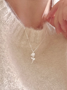 Elegant 925 sterling silver rose bud pendant necklace worn over a white knitted sweater