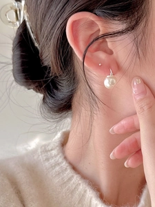 Macro view of 925 sterling silver hook earrings with a large round pearl on ear
