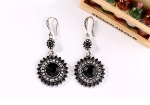 Close-up of vintage sunflower drop earrings with black stones in bohemian silver style