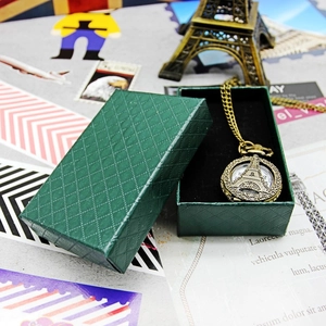 Vintage bronze pocket watch with Eiffel Tower relief displayed in a green textured gift box