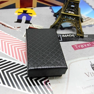 Close-up of black diamond-textured jewelry gift box with vintage travel background