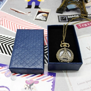 Close-up of vintage bronze Eiffel Tower pocket watch with a luxury blue jewelry box