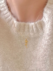 Detailed close-up of a 925 silver golden rose pendant necklace on a knitted sweater