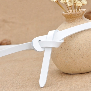 Minimalist white leather skinny belt for women tied on a vase with natural decor