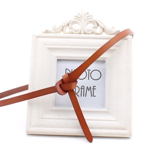 Detailed view of a slim brown leather belt tied on a decorative vintage frame