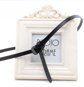 Detail shot of a slender black leather belt knotted elegantly on a white photo frame