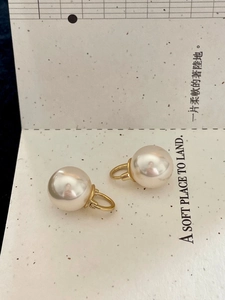 Macro detail of high-luster round pearls on gold-plated hook earrings with elegant texture