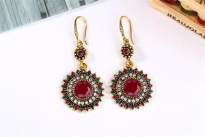 Detail of bohemian sunflower earrings with red center stone and vintage gold finish