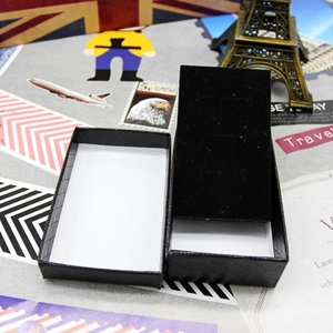 Detail view of black textured jewelry box with flocked lining on travel-themed background