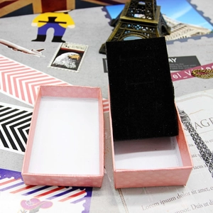 Pink diamond pattern jewelry gift box with black velvet lining shown on retro background