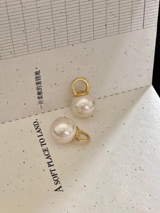 Close-up of elegant 925 silver pearl hoop earrings on a minimalist cream card background