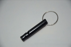 Detail of a portable black aluminum emergency whistle with a silver metal keyring